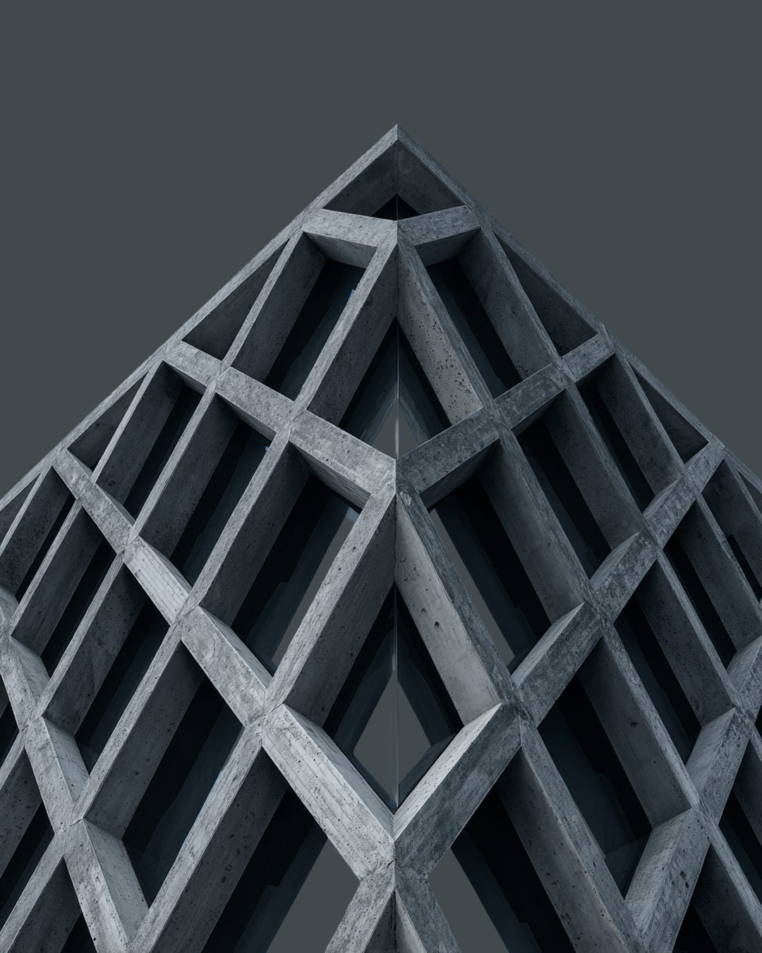 Dark concrete lattice tower against a pale sky